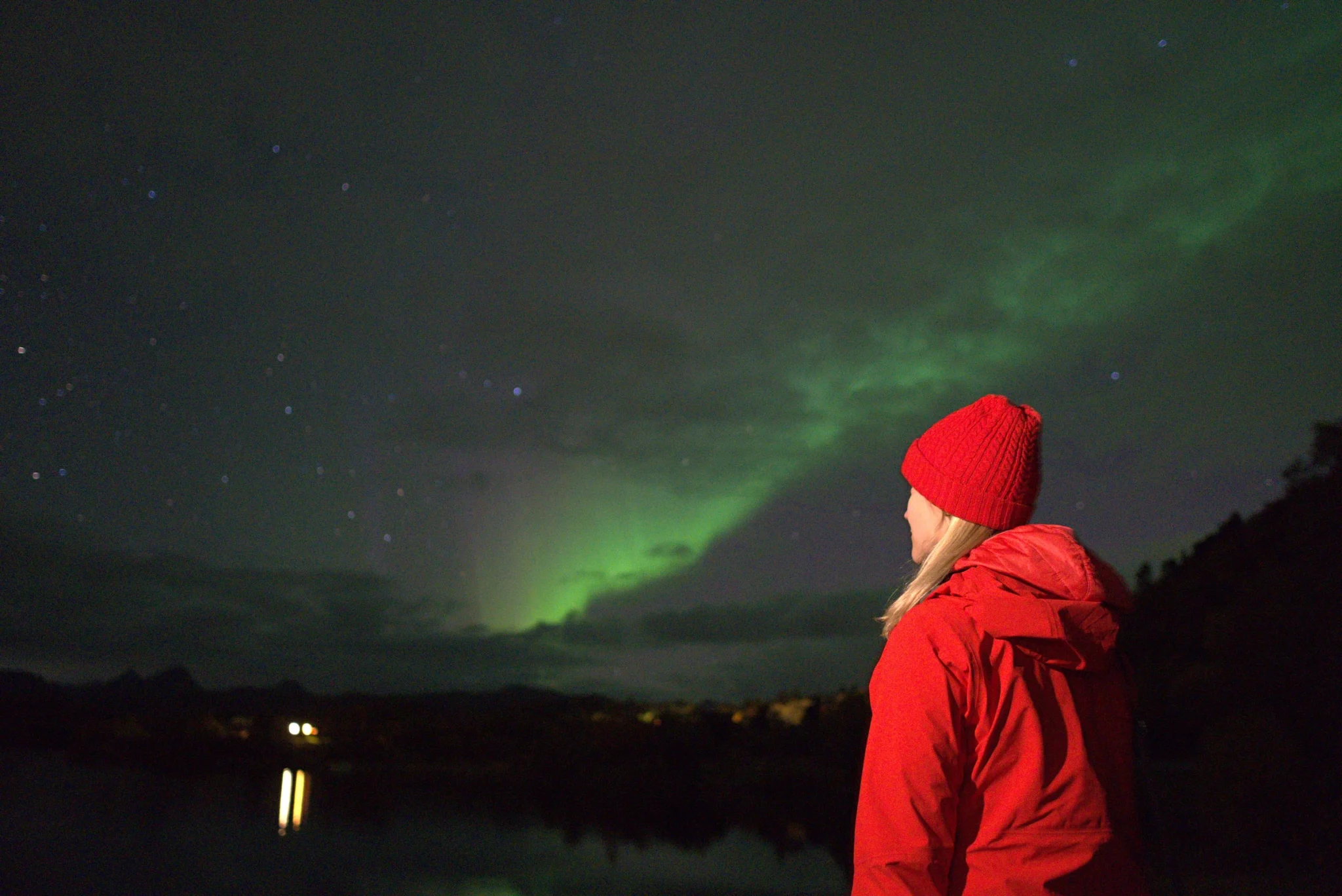 Guest in a red jacket watching the Northern Lights over Lofoten
