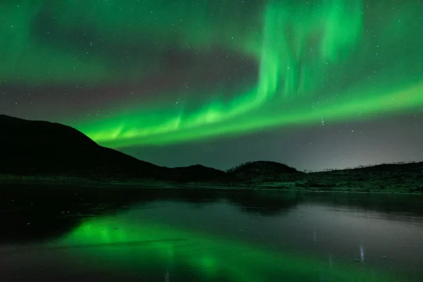 Northern Lights over mountain with reflections in the sea